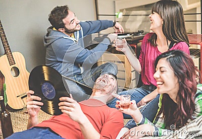 Happy friends having party listening vintage vinyl disc albums in hostel living room - Young people having fun drinking and Stock Photo