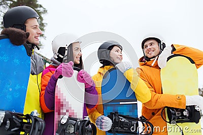 Happy friends in helmets with snowboards talking Stock Photo