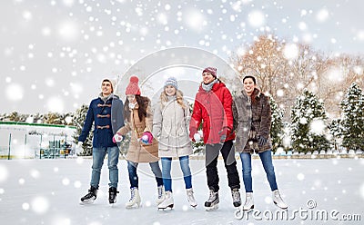 Happy friends ice skating on rink outdoors Stock Photo