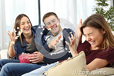Happy friends joking throwing popcorn Stock Photo