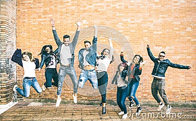 Happy friends millennials jumping and cheering against brick wall Stock Photo