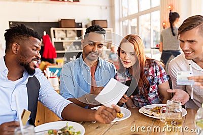 Happy friends with money paying bill at restaurant Stock Photo