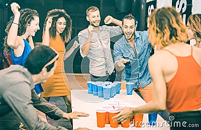 Happy friends playing beer pong in youth hostel - Travel and joy concept with backpackers having unplugged fun at guesthouse Stock Photo