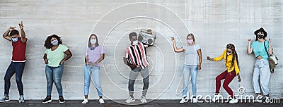 Happy friends wearing face mask listening music with vintage boombox outdoor - Multiracial young people having fun dancing Stock Photo