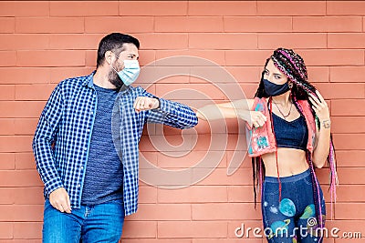 Happy friends wearing protective face mask while greeting by bumping their elbows Stock Photo