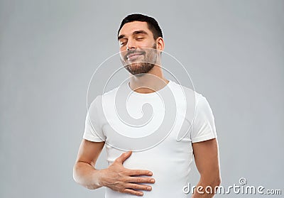 Happy full man touching tummy over gray background Stock Photo