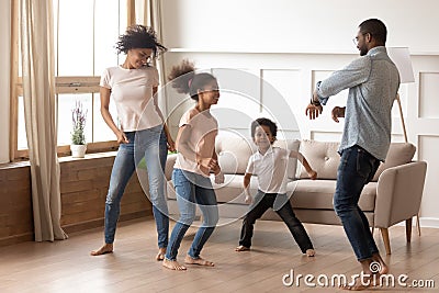 Happy funny active african family of four dancing at home Stock Photo