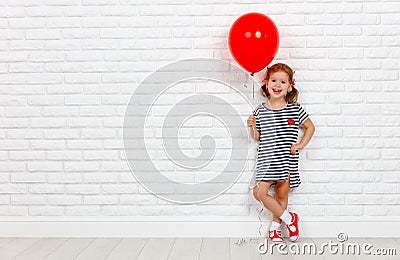 Happy funny child girl with red ball near an brick wall Stock Photo