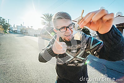 Happy funny man holds house keys on house shaped keychain in front of a new home Stock Photo