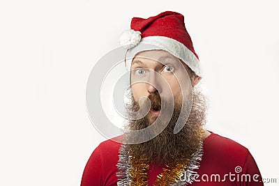 Happy funny santa claus with real beard and red hat and shirt making crazy face and smiling, looking and camera Stock Photo
