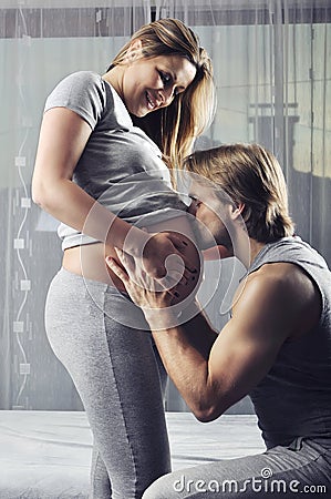 Happy future daddy kissing his pregnant wifes belly Stock Photo