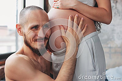 Happy future father listening to baby belly of his wife. Authentic couple, family waiting for baby Stock Photo