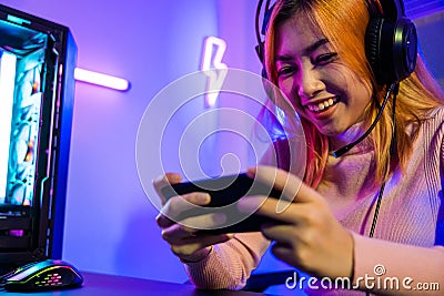 Happy Gamer playing video game online with smartphone with neon lights Stock Photo