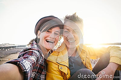 Happy gay couple taking selfie on the beach at sunset - Young lesbians having fun dating first time Stock Photo