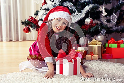Happy gerl dressed as santa with gifts in boxes siting near a decorated Christmas tree at home closeup. Celebration of Christmas, Stock Photo
