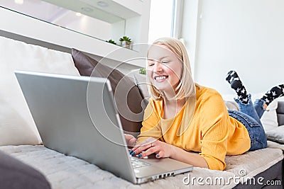 Happy girl chatting online on laptop. Smiling blonde woman messaging with friends on computer. Social media, communication and Stock Photo
