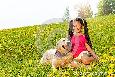 Happy girl cuddling dog sitting on the grass Stock Photo