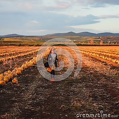 Happy girl in dark blue coat running on the pumpkin field Stock Photo