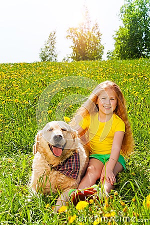 Happy girl and dog sitting on the grass Stock Photo