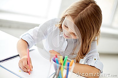 Happy girl drawing with felt-tip pen in notebook Stock Photo