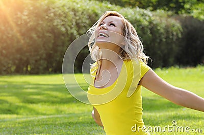 Happy girl enjoying the Nature on green grass. Beautiful young woman smiling with arms outstretched Stock Photo