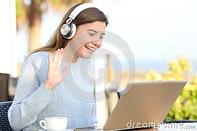 Happy girl greeting during videocall on laptop in a terrace Stock Photo