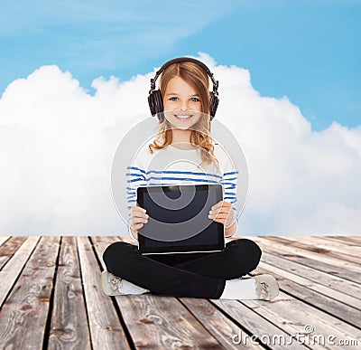 Happy girl with headphones showing tablet pc Stock Photo