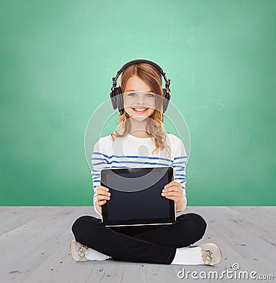 Happy girl with headphones showing tablet pc Stock Photo