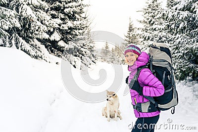 Happy girl hiking in winter forest with dog Stock Photo