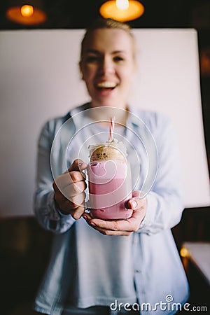 Happy girl is holding stylized mason jar cup of pink coffee with marshmallow and decoration. Milk shake, cocktail. Unicorn coffee, Stock Photo