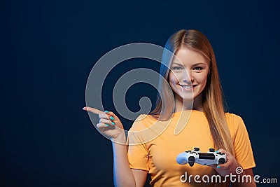 Happy girl holding video game joystick pointing finger to side Stock Photo