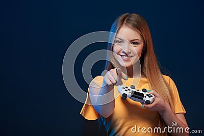 Happy girl holding video game joystick pointing finger at you Stock Photo