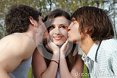 Happy girl kissed by two young boys Stock Photo