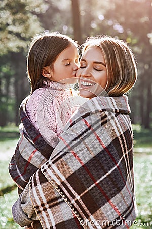 Happy, girl kisses her beautiful mother in forest are covered with blanket Stock Photo