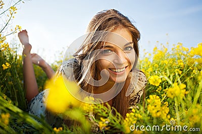 Happy girl lies among yellow wildflowers Stock Photo