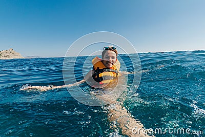 happy girl in a life jacket swims in the water in the sea Stock Photo
