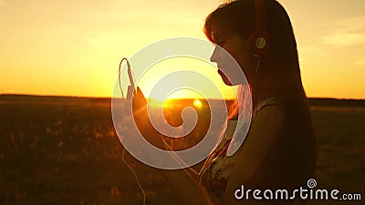 Happy girl listening to music and dancing in the rays of a beautiful sunset. young girl in headphones and with a Stock Photo