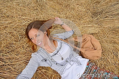 Happy girl lying on a straw pile Stock Photo