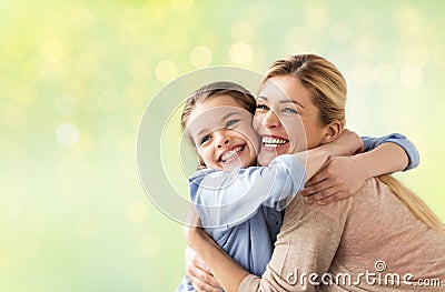 Happy girl with mother hugging over lights Stock Photo