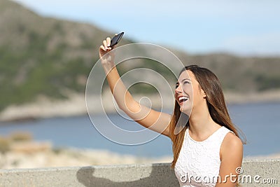 Happy girl photographing a selfie on the beach Stock Photo