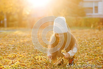 Happy girl playing with autumn leaves. Happy child walking and having fun in fall backyard Stock Photo