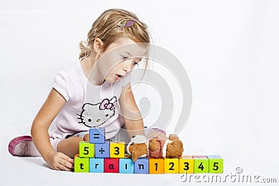 Happy girl playing with colourful wooden blocks Stock Photo