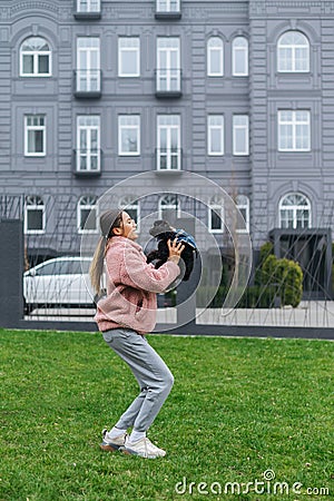 Happy girl playing with dog in her arms on a walk. The owner holds in her hands a little dog breed toy poodle, standing on the Stock Photo