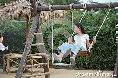 Happy girl playing on the wooden swing in the playground Stock Photo