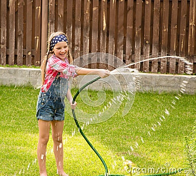 Happy girl pours water from a hose Stock Photo