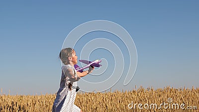 Happy girl runs with a toy airplane on a wheat field under a blue sky. children play a toy airplane. teenager dreams of Stock Photo