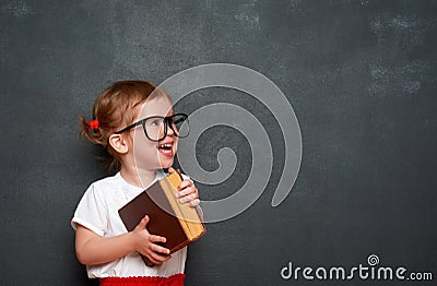 Happy girl schoolgirl with book from blackboard Stock Photo