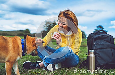 Happy girl with smile drink cup playing with red japanese dog shiba inu on green grass in the outdoors nature park, beautiful Stock Photo