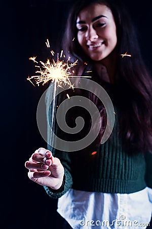 Happy girl smiling and holding a sparkling firework in her hand. Stock Photo