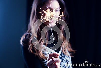 Happy girl smiling and holding a sparkling firework in her hand. Stock Photo